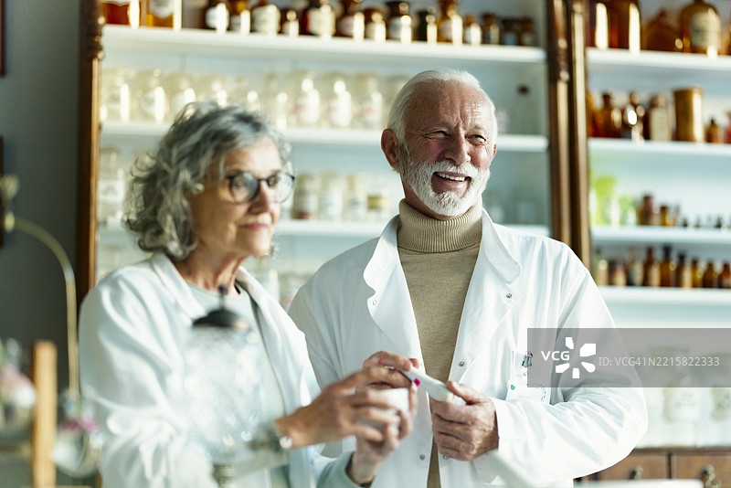 快乐的成熟化学家在实验室里研究药物。图片素材