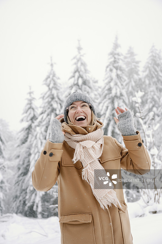 成熟的女性在森林中欢笑，享受雪白的冬日。图片素材
